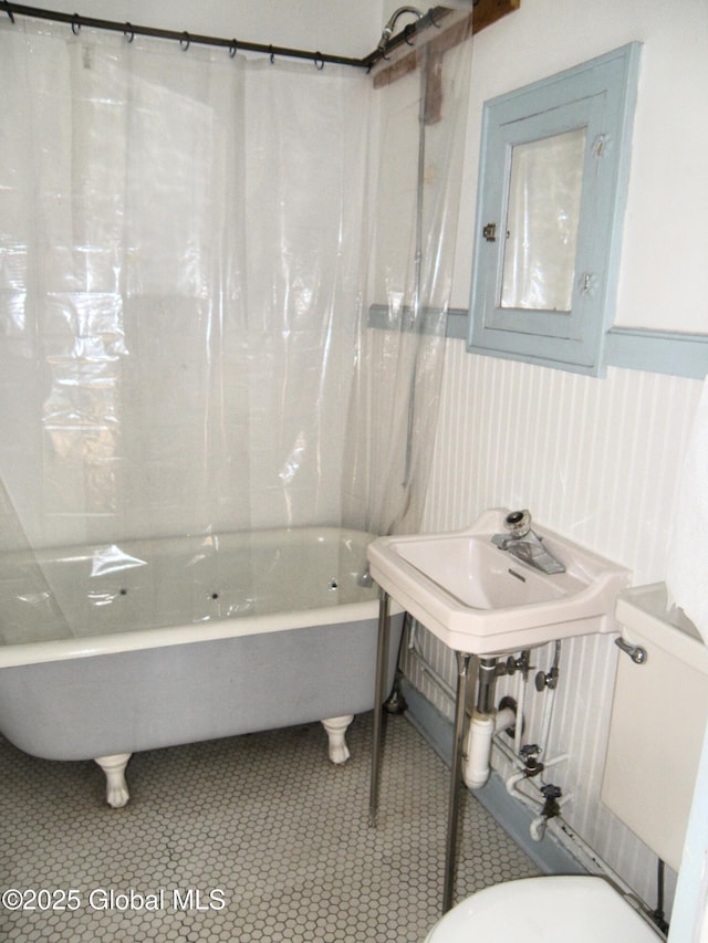 bathroom with a bathing tub, sink, tile patterned floors, and toilet