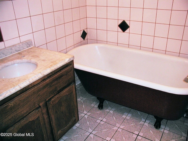 bathroom featuring vanity, tile walls, tile patterned floors, and a tub to relax in