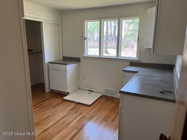 kitchen with visible vents, light wood finished floors, dark countertops, and white cabinetry