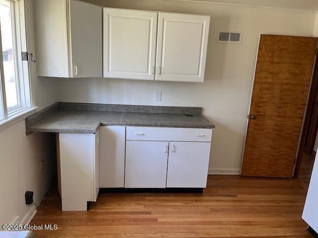 kitchen featuring visible vents, dark countertops, baseboards, white cabinets, and light wood finished floors