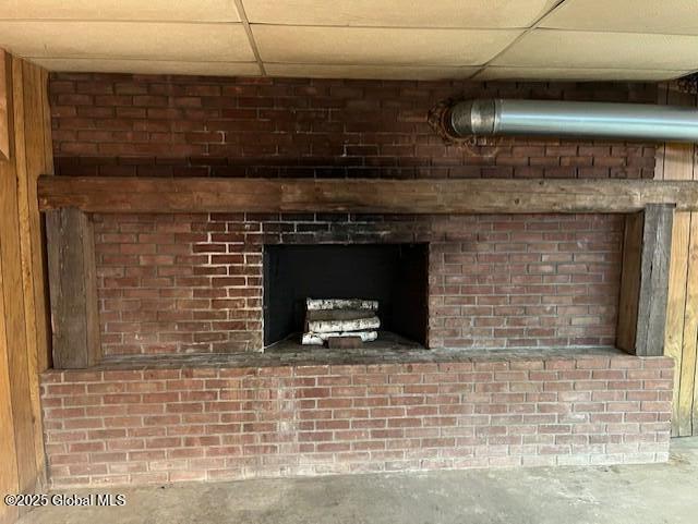 details featuring a paneled ceiling, a fireplace, and unfinished concrete floors