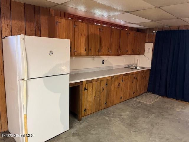 kitchen featuring a sink, light countertops, freestanding refrigerator, and concrete flooring
