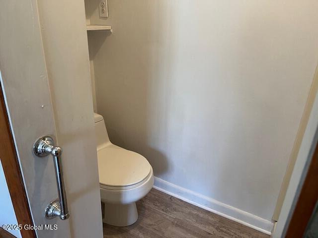 bathroom with toilet, baseboards, and wood finished floors