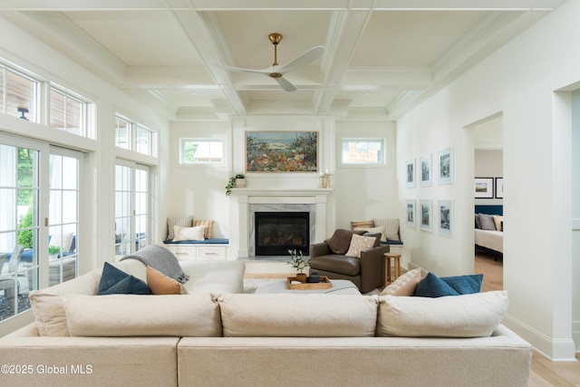 sunroom featuring beamed ceiling, a premium fireplace, coffered ceiling, and ceiling fan