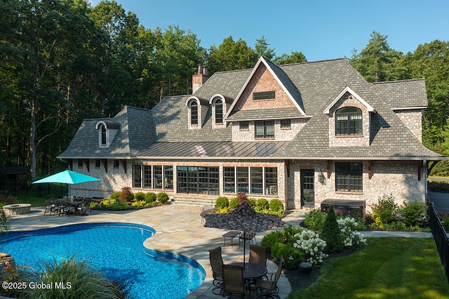 back of house with a swimming pool with hot tub and a patio