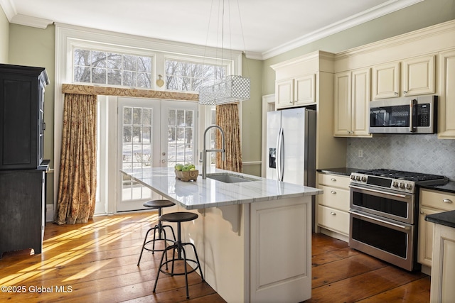 kitchen featuring sink, appliances with stainless steel finishes, an island with sink, pendant lighting, and backsplash