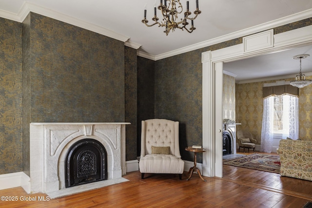 unfurnished room with hardwood / wood-style flooring, a large fireplace, ornamental molding, and an inviting chandelier