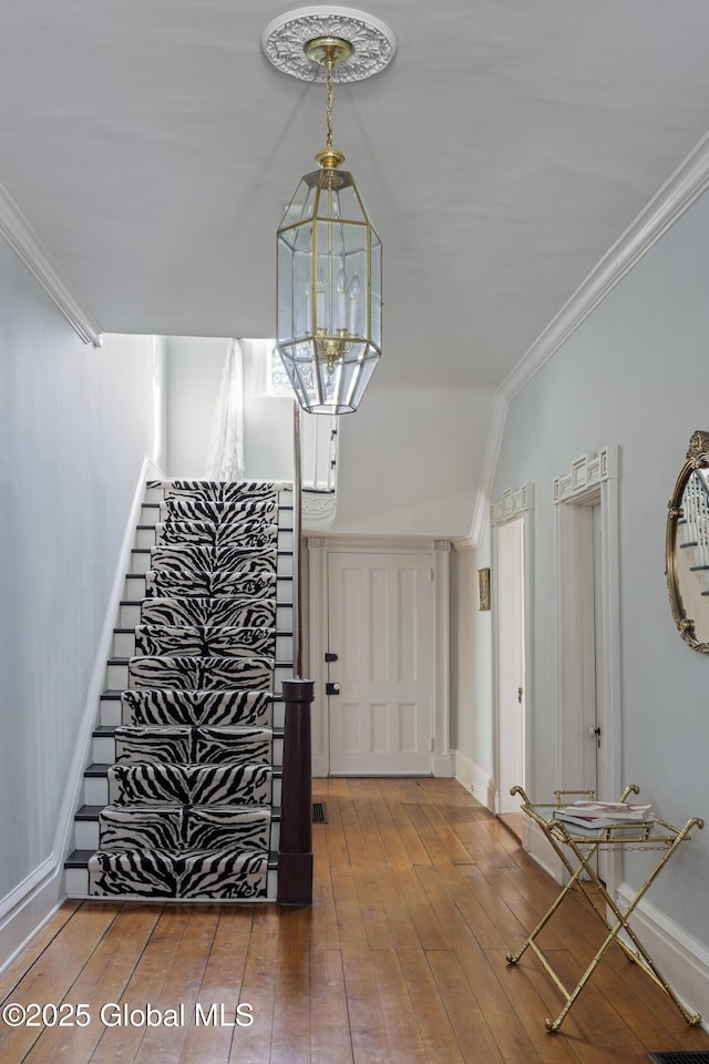 entrance foyer featuring an inviting chandelier, hardwood / wood-style flooring, and ornamental molding