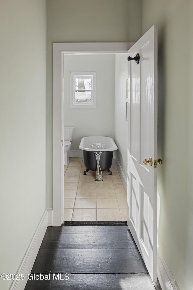 bathroom featuring a washtub, tile patterned flooring, and toilet