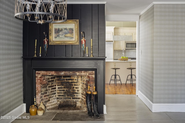 interior details with decorative backsplash, hardwood / wood-style flooring, crown molding, a brick fireplace, and an inviting chandelier