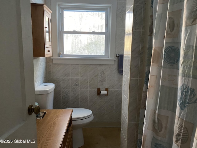 bathroom with a shower with curtain, toilet, and tile walls