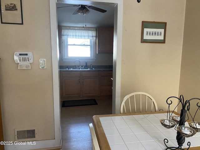 unfurnished dining area with sink, wood-type flooring, and ceiling fan