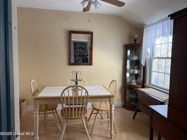 dining area with ceiling fan, lofted ceiling, and light hardwood / wood-style floors