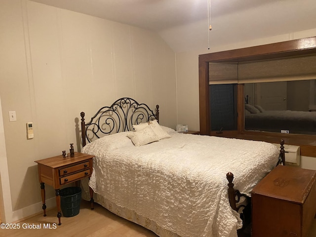 bedroom with vaulted ceiling and light hardwood / wood-style floors