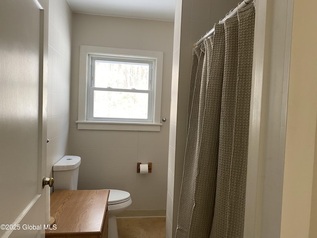 bathroom with a shower with curtain, vanity, tile walls, and toilet