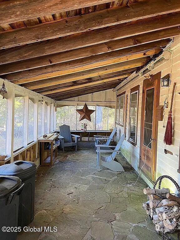 unfurnished sunroom featuring vaulted ceiling with beams