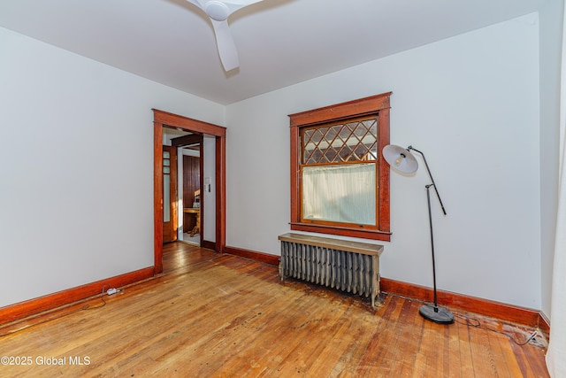 unfurnished room with ceiling fan, radiator heating unit, and wood-type flooring