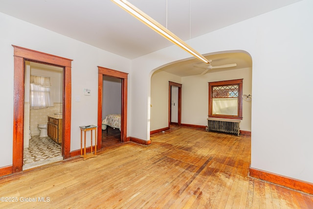 empty room with radiator, hardwood / wood-style flooring, and ceiling fan