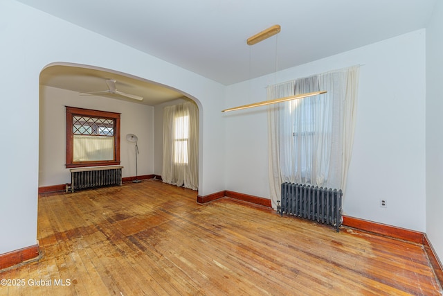 spare room featuring wood-type flooring, radiator heating unit, and ceiling fan