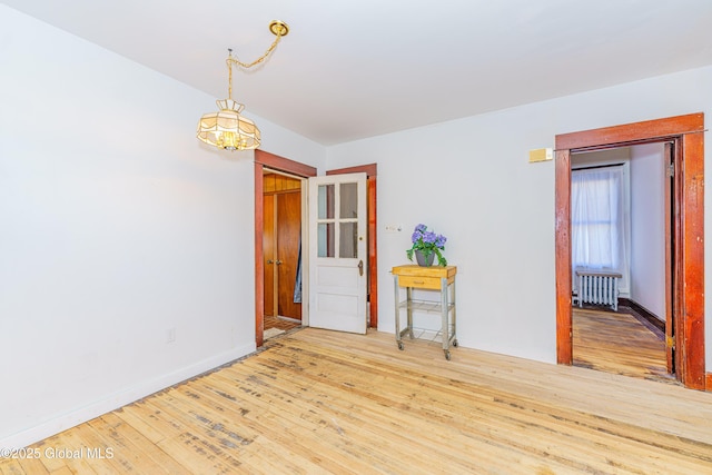 empty room with radiator heating unit, a chandelier, and wood-type flooring