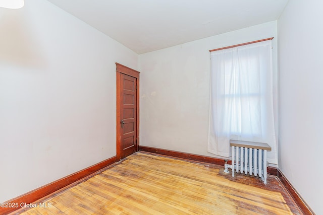 unfurnished room with radiator and light wood-type flooring