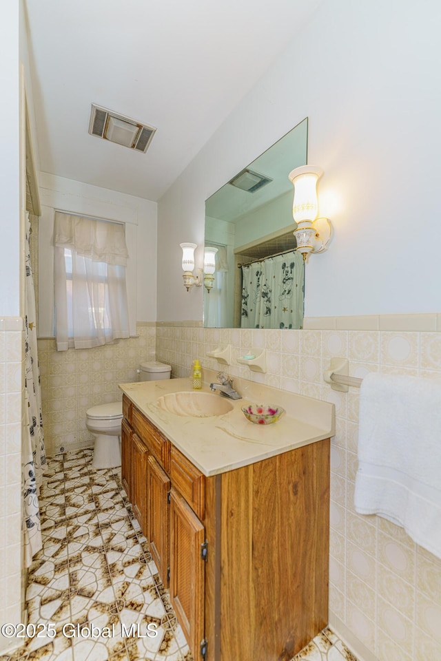 bathroom featuring tile walls, vanity, and toilet