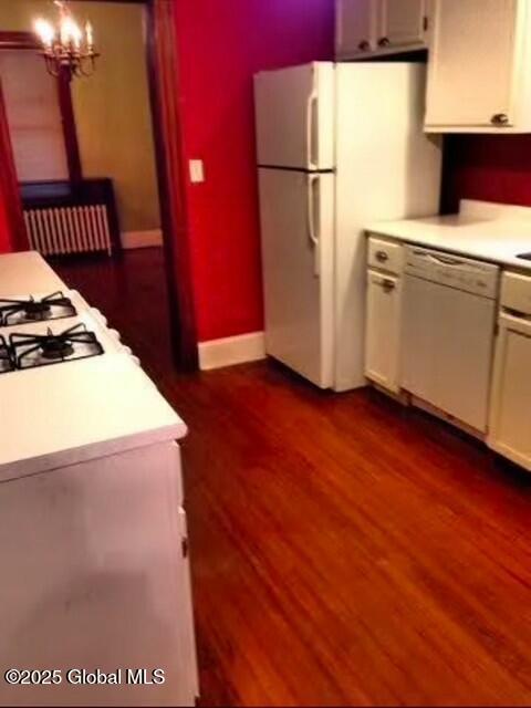 kitchen featuring white cabinetry, hanging light fixtures, white appliances, and dark wood-type flooring