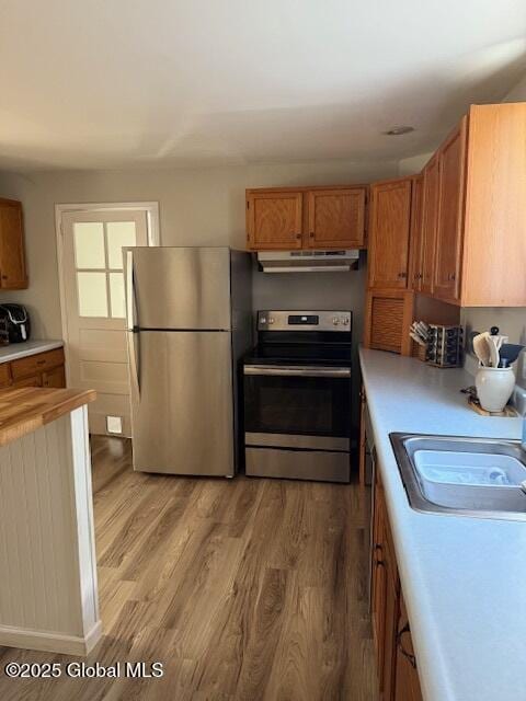 kitchen with appliances with stainless steel finishes, sink, and wood-type flooring