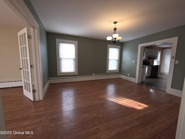 spare room with dark wood-type flooring, a chandelier, and baseboard heating