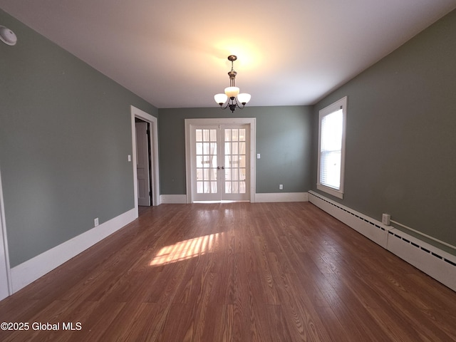 spare room with a baseboard heating unit, a notable chandelier, dark hardwood / wood-style flooring, and french doors