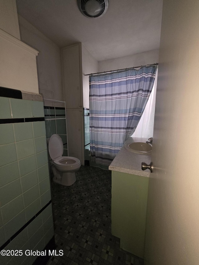 bathroom featuring vanity, tile walls, toilet, and walk in shower