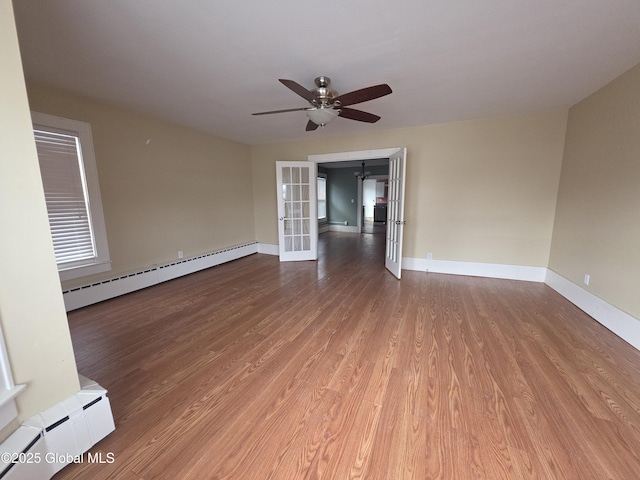 empty room with french doors, hardwood / wood-style floors, and a baseboard heating unit