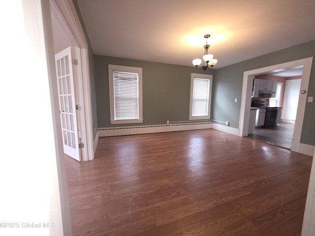 empty room with a notable chandelier, dark hardwood / wood-style flooring, and a baseboard heating unit