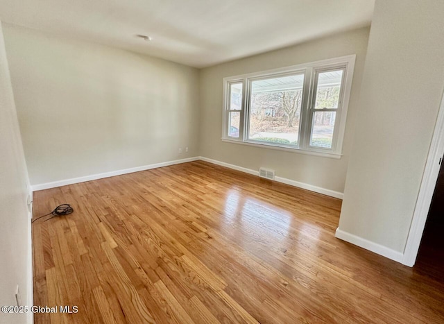 spare room with visible vents, baseboards, and wood finished floors