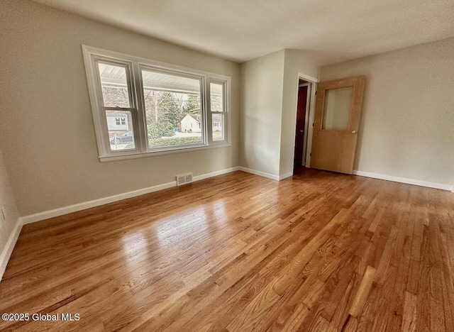 unfurnished room featuring wood finished floors, visible vents, and baseboards