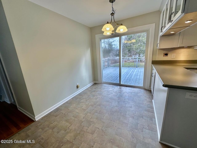 unfurnished dining area with stone finish flooring and baseboards