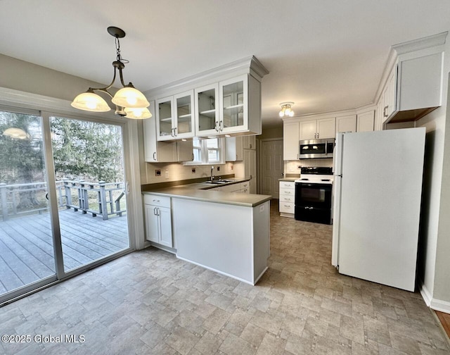 kitchen with stainless steel microwave, a peninsula, freestanding refrigerator, electric range, and a sink