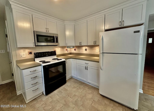 kitchen with electric stove, stainless steel microwave, backsplash, freestanding refrigerator, and white cabinets