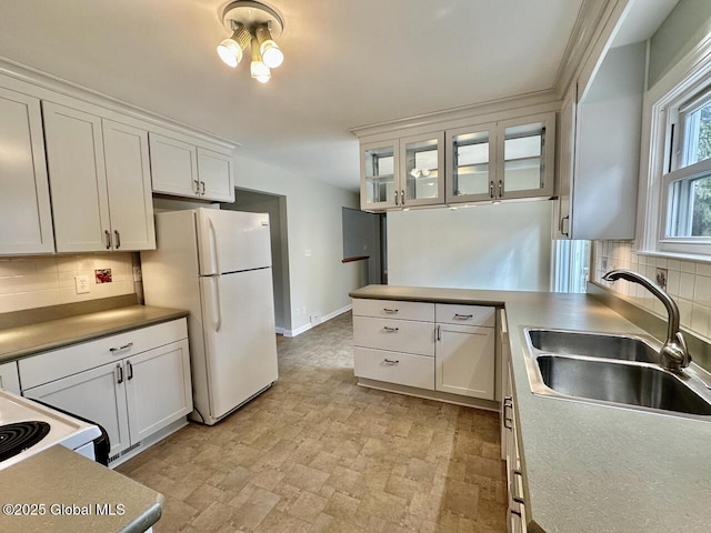 kitchen with a sink, white appliances, tasteful backsplash, and white cabinetry