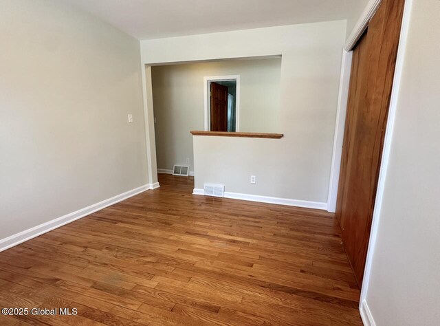 unfurnished room featuring visible vents, baseboards, and wood finished floors