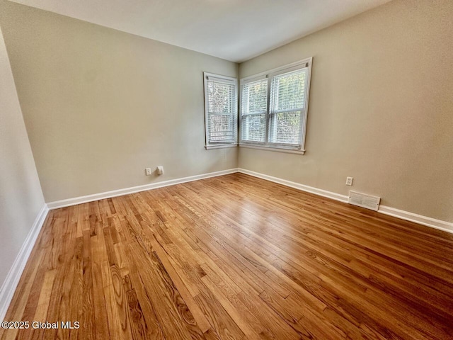 spare room featuring visible vents, baseboards, and wood finished floors