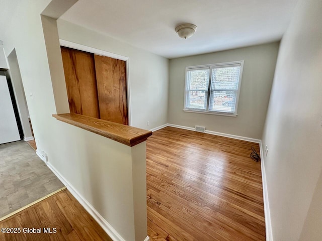 spare room with wood finished floors, visible vents, and baseboards