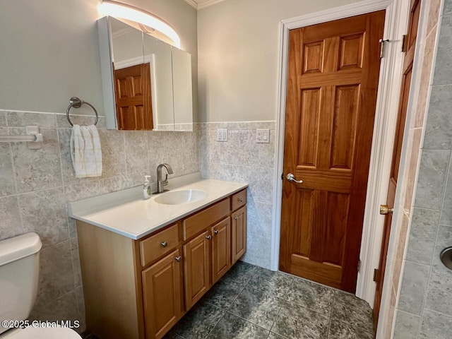 bathroom with toilet, tile walls, vanity, and tile patterned flooring