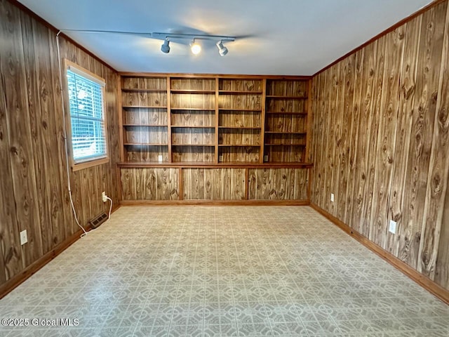 empty room featuring tile patterned floors, built in shelves, baseboards, and wood walls