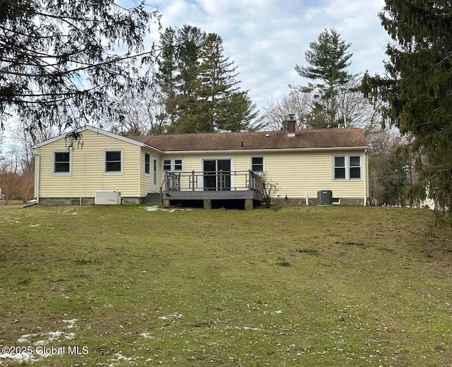 rear view of house with a wooden deck, a yard, central AC unit, and a chimney