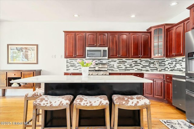 kitchen featuring backsplash, stainless steel appliances, a kitchen breakfast bar, and a kitchen island