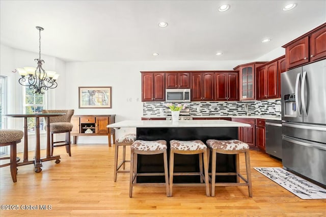 kitchen with a center island, appliances with stainless steel finishes, a breakfast bar, and light hardwood / wood-style flooring