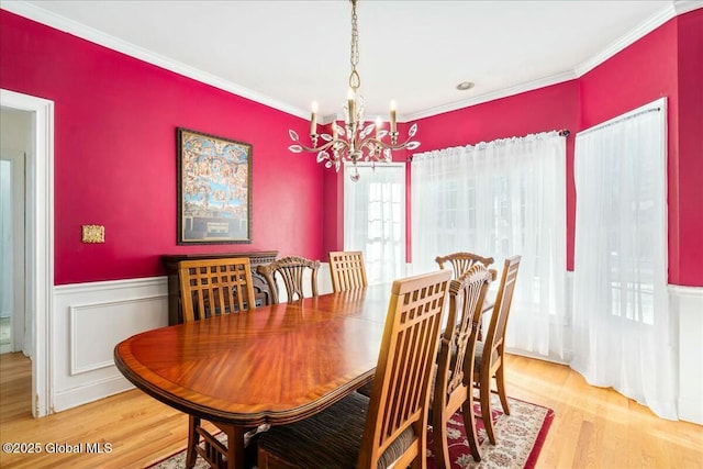 dining area featuring crown molding, light hardwood / wood-style floors, and a chandelier