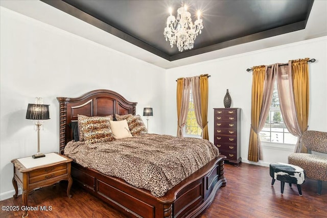 bedroom with a notable chandelier, dark hardwood / wood-style flooring, and a tray ceiling