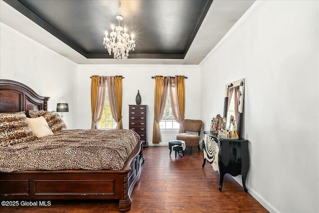 bedroom with dark wood-type flooring, a notable chandelier, and a tray ceiling